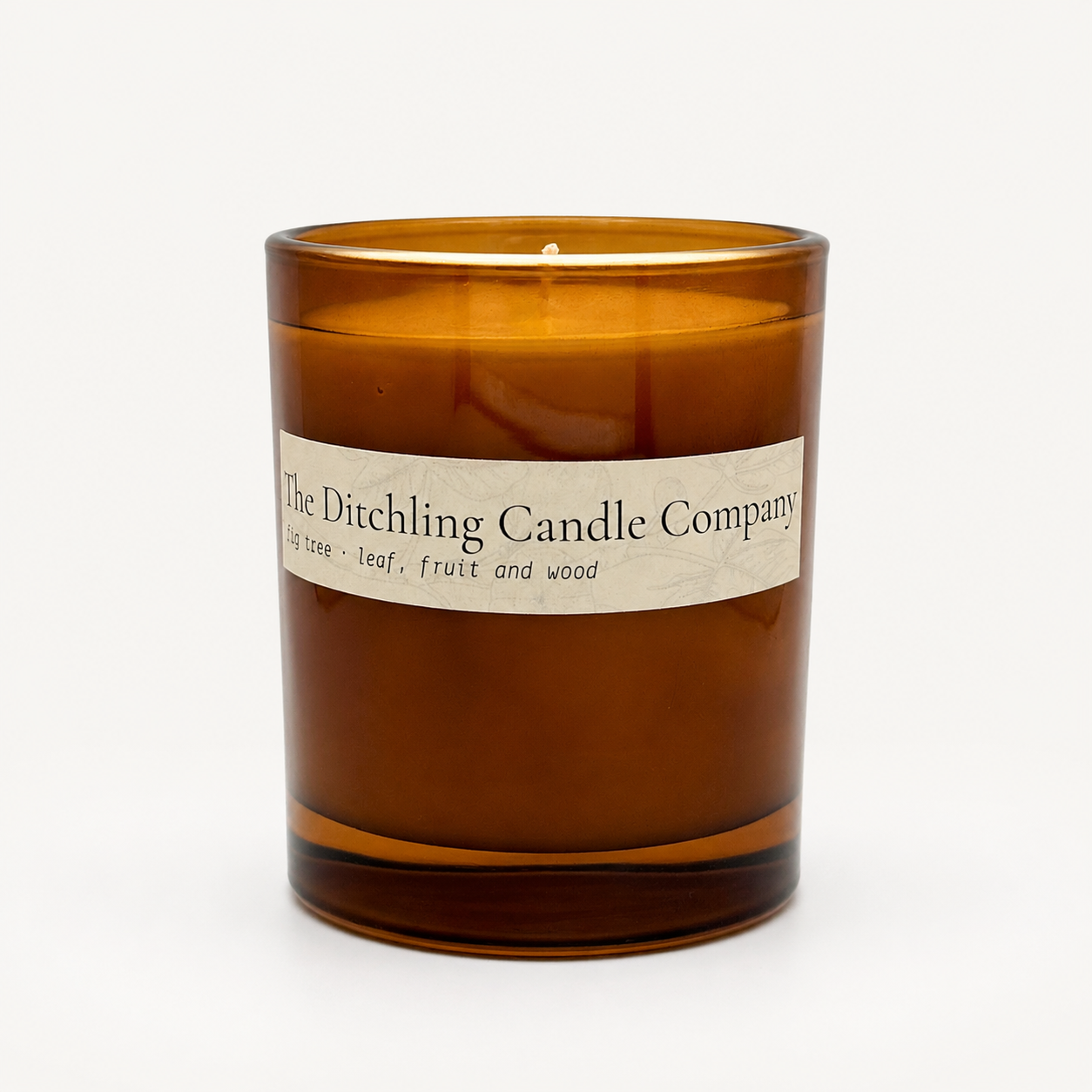 Amber glass fig tree scented soy candle by The Ditchling Candle Company, shown open on a clean white background.